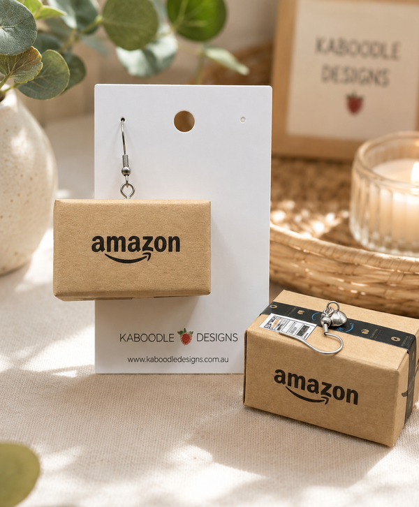 Miniature Amazon parcel drop earring on white display card with Kaboodle Designs branding, second box shown beside with