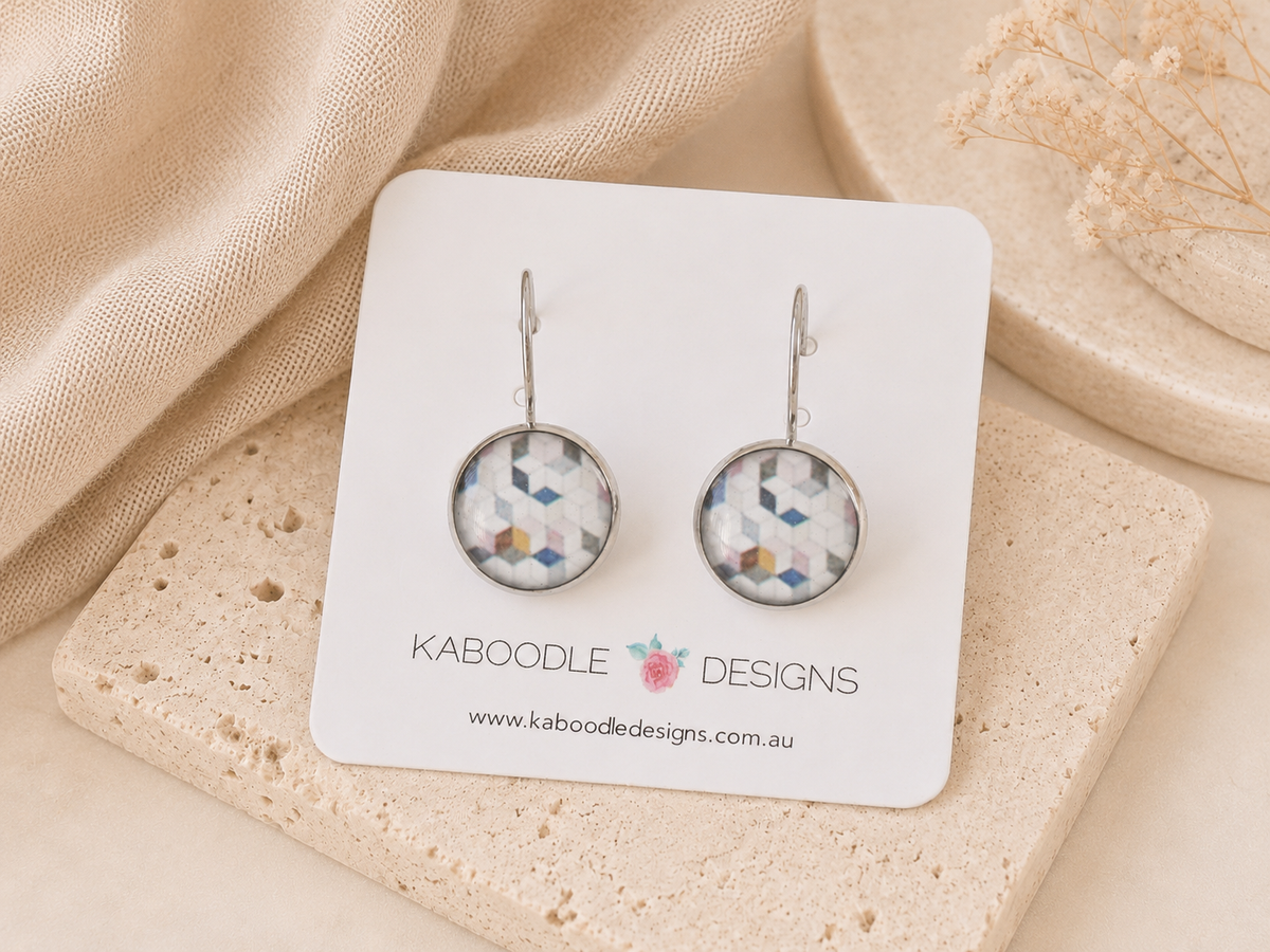 Round geometric mosaic earrings in blue, pink and mustard tones on a Kaboodle Designs card