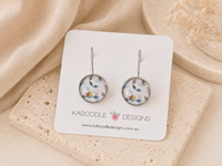 Round geometric mosaic earrings in blue, pink and mustard tones on a Kaboodle Designs card