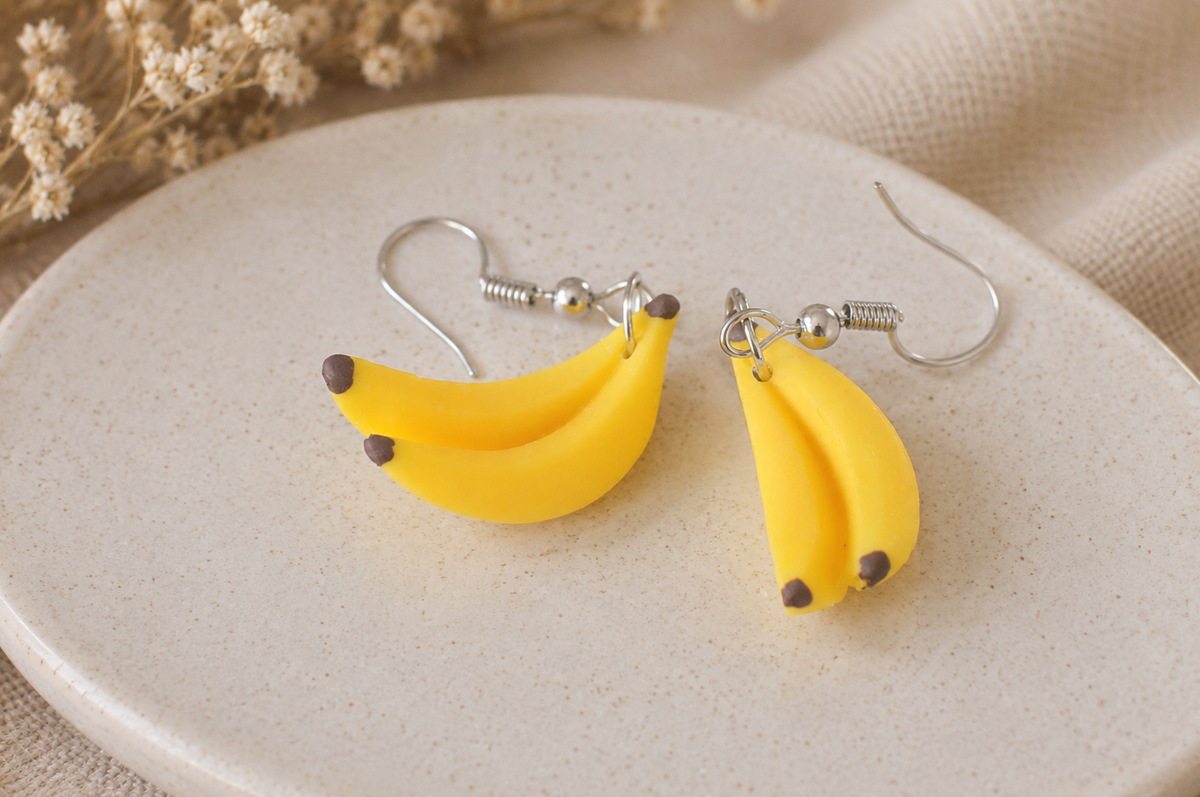 Pair of banana bunch drop earrings with silver fishhook wires on a ceramic dish