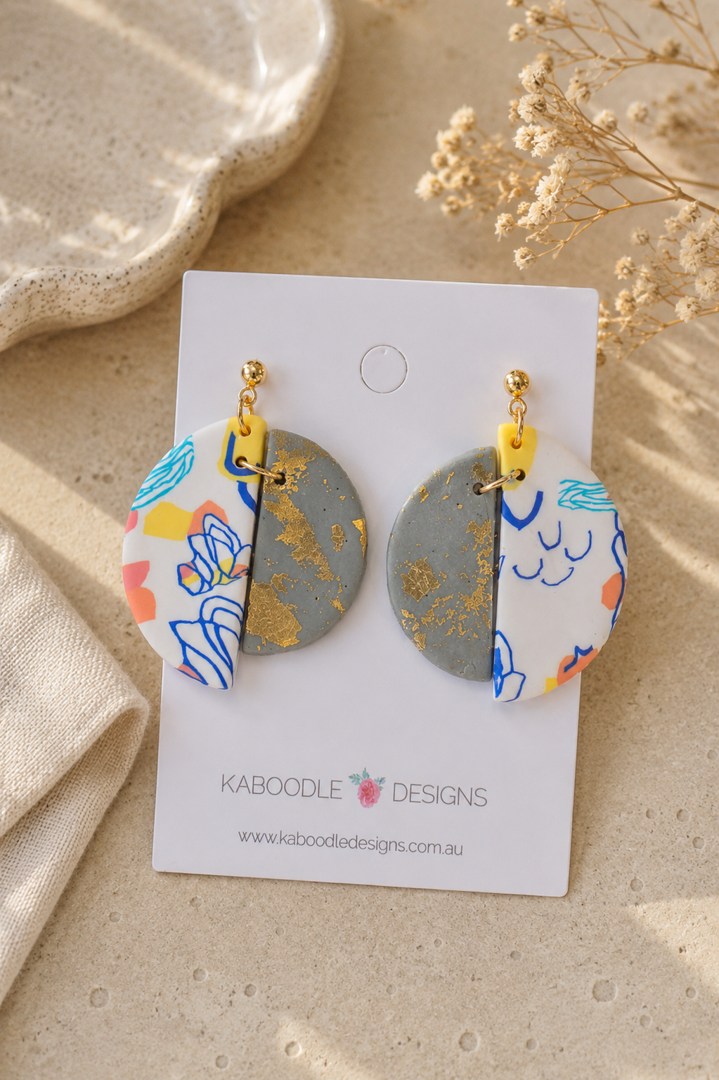 Clay split-circle drop earrings on card, gold foil half and abstract line art half