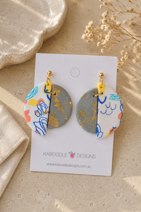 Clay split-circle drop earrings on card, gold foil half and abstract line art half