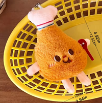 Overhead view of drumstick plush keychain in yellow basket showing 12.5cm length measurement