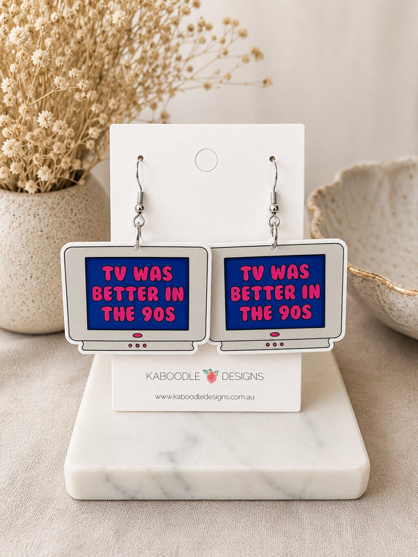 Pair of retro TV-shaped dangle earrings with pink text reading TV Was Better in the 90s on a blue screen