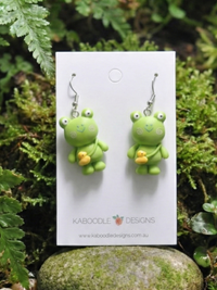 Green resin frog earrings holding yellow rubber ducks on Kaboodle Designs card