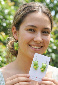 Close-up of frog drop earring worn on ear showing green resin detail