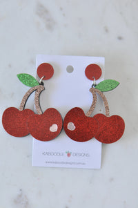 Pair of glitter red cherry drop earrings with green leaves on Kaboodle Designs card