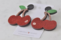 Glitter cherry earrings laid flat on card showing black stud and stem detail
