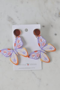 Pair of acrylic butterfly drop earrings with lilac, orange and yellow wing detail on card backing
