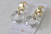 Close-up angled view of gold drop earrings showing faceted circle detail and gold link