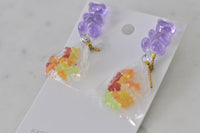 Overhead view of both gummy bear cluster earrings on white marble background