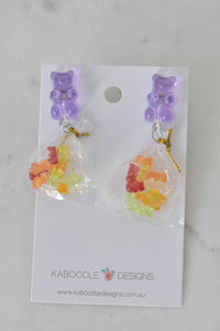 Purple gummy bear stud earrings with mini bags of rainbow gummy bears on Kaboodle card