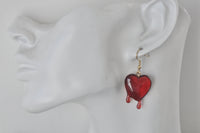 Close-up of red dripping heart earring worn on a mannequin ear, showing glossy resin drip detail