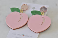 Close-up of two pink peach earrings showing rose-gold crease detail and glitter leaves