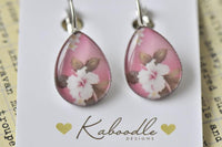 Pink teardrop clip earrings with white and blush cherry blossom design, front view on card