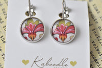 Round silver-framed clip earrings with pink and gold flower design on white card