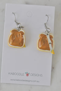 Resin peanut butter toast drop earrings on Kaboodle Designs card, one with knife charm