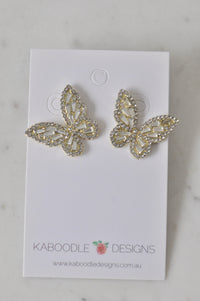 Overhead view of two rhinestone butterfly stud earrings on a card, showing baguette-cut centre stones
