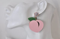 Pink peach earring shown worn on ear, side profile view