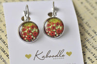 Round dangle earrings with red and white poppy field image, front view on card