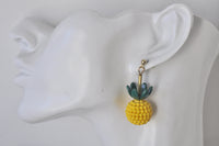 Close-up side view of pineapple earring worn on a model ear, showing textured yellow body