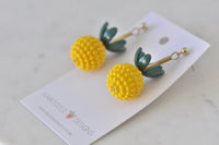 Pair of pineapple resin earrings laid flat on Kaboodle Designs branded card