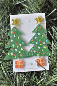 Pair of green glitter Christmas tree drop earrings with gold star studs and red present charms on card
