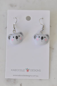 Pair of grey resin koala face drop earrings with pink cheek detail on Kaboodle card