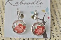 Round red and pink floral dome clip earrings on silver-plated setting, shown on card
