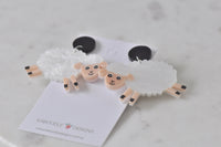 Angled view of sheep earrings showing black stud tops and pink legs