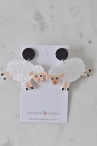 White acrylic sheep drop earrings on a Kaboodle Designs card, front view