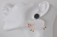 Close-up of a single sheep earring with textured wool worn on an ear