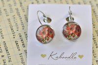 Round French clip earrings with red and pink floral print, displayed on Kaboodle Designs card