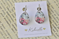Handmade teardrop clip earrings with pink floral design on teal striped background, shown on Kaboodle card