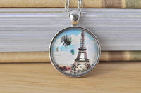Round glass pendant necklace with Eiffel Tower and hot air balloon design on silver chain
