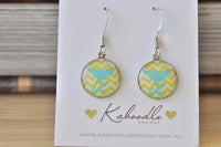 Round dangle earrings with turquoise bird silhouette on yellow chevron print, shown on card
