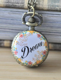 Antique bronze pocket watch necklace with floral wreath and 'Dream' script design on the front cover