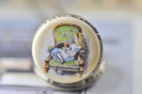 Close-up of Alice in Wonderland pocket watch pendant artwork showing Alice on a green chair with her dog