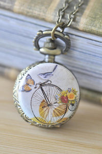 Bronze pocket watch necklace featuring a bird, butterfly and floral penny farthing design