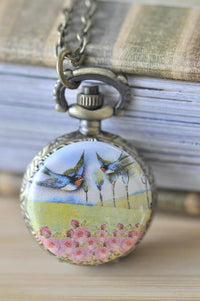 Antique brass pocket watch necklace with swallow birds flying over a pink rose field design