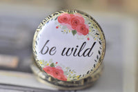 Close up of be wild pocket watch pendant with pink floral wreath detail