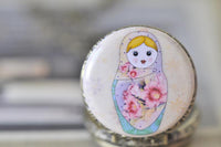 Close-up of the illustrated babushka doll design on the pocket watch pendant