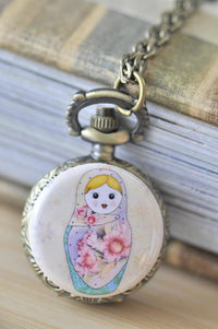 Babushka doll pocket watch necklace pendant resting against vintage books