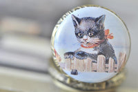 Close-up of the vintage kitten and fence design on the pocket watch pendant lid