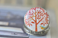 Close-up of red tree and blue bird design on pocket watch pendant lid