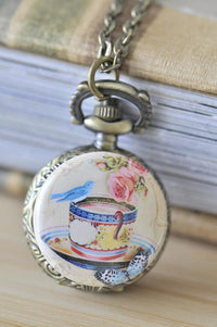 Bird on a tea cup pocket watch necklace with roses and butterfly artwork on bronze filigree case