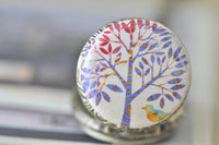 Close-up of tree and bird artwork on pocket watch pendant lid