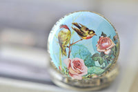Close-up of the bird and rose design on the pocket watch necklace pendant