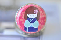 Close-up of kokeshi doll artwork on pocket watch pendant lid