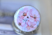 Close-up of watercolour pink flower artwork on brass pocket watch pendant